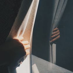 Close-up of man holding curtain