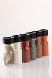 Close-up of spices in bottles against white background