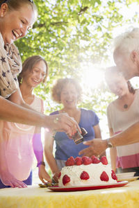 Women preparing strawberry cake in garden