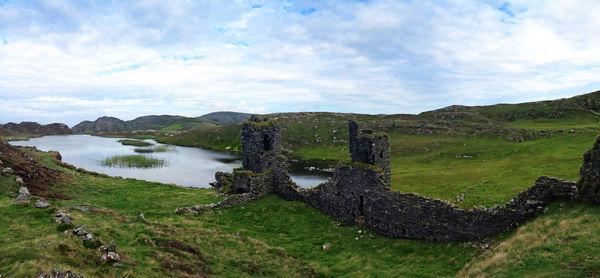 Old ruin castle by lake against sky
