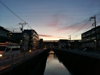 Illuminated bridge over road against sky at sunset