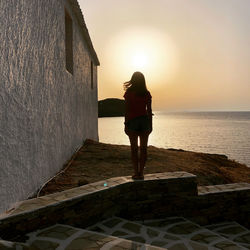 Rear view of woman standing on sea shore against sky