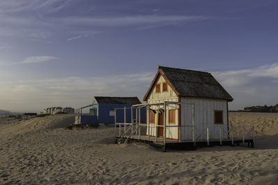 Hut on beach by sea against sky