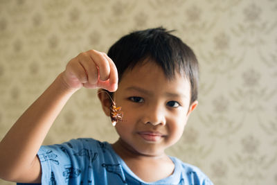 Portrait of cute boy holding cockroach at home