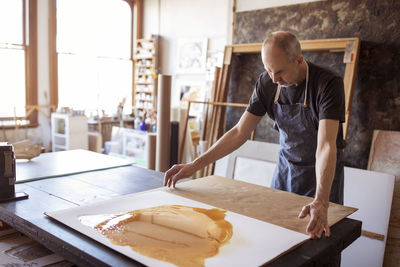 Senior artist making paintings at table in workshop