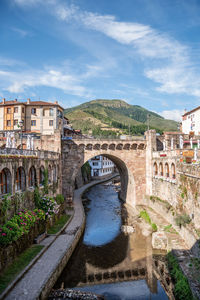 Arch bridge over river against buildings in city