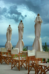 Chairs and tables by sea against sky