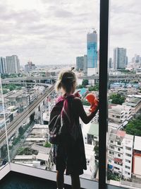 Girl looking through window in city