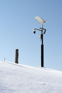 Low angle view of snow with street light against clear sky