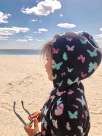 Rear view of woman on beach against sky