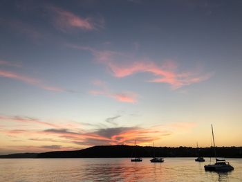 Silhouette sailboats in sea against sky during sunset