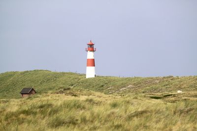 Lighthouse on landscape against clear sky