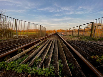 Railroad tracks on field against sky during sunset