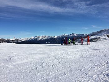 People on snowcapped mountain against sky