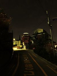 Empty road along buildings at night
