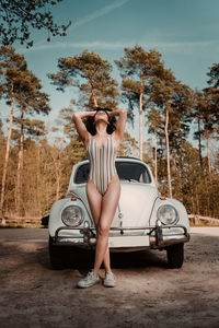 Teenage girl in swimsuit standing by car outdoors