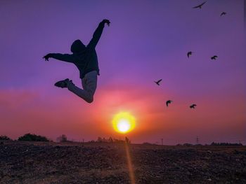 Low angle view of man jumping against sky during sunset