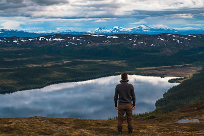 Rear view of man standing on mountain against sky