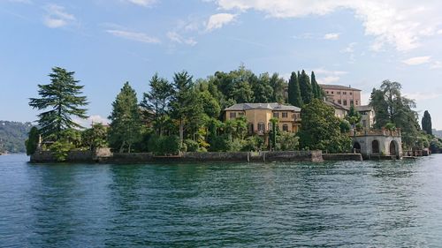 Houses by river and buildings against sky