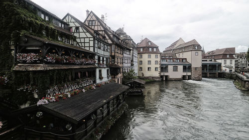 Bridge over river by buildings in city against sky