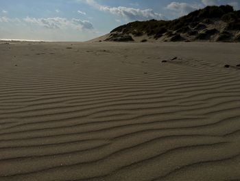 Scenic view of sand dunes in desert against sky