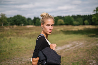 Portrait of young woman standing on field