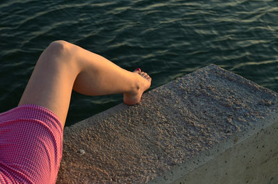 Low section of woman sitting by sea