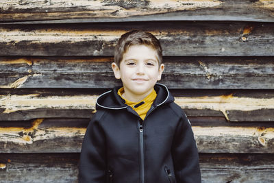 Portrait of smiling boy standing against wood