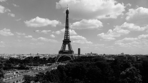 Tower in city against cloudy sky