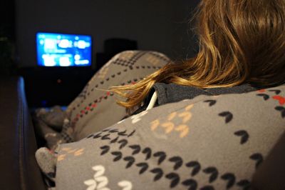 Rear view of woman watching tv at home