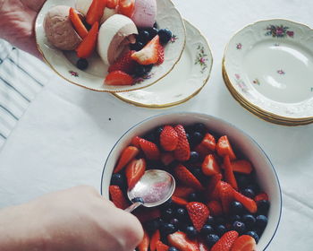 High angle view of hand holding fruit in plate on table