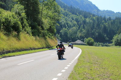 Rear view of bikers riding motorcycles on road