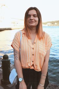 Beautiful young woman standing against sea