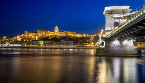 Szechenyi chain bridge over danube river against sky in city at night