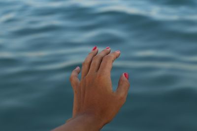 Cropped image of woman hand by sea