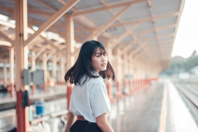 Rear view of young woman walking at railroad station platform