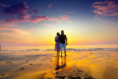 Rear view of couple on beach during sunset