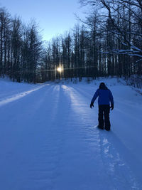 Rear view of man walking on snow covered landscape