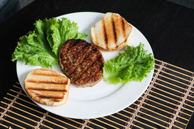 High angle view of grilled meat with lettuce in plate on place mat at home
