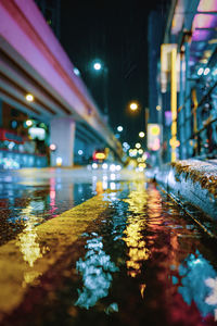 Reflection of illuminated buildings in puddle at night