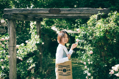 Side view portrait of woman standing by flowering plants