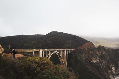 Bridge over mountain against sky