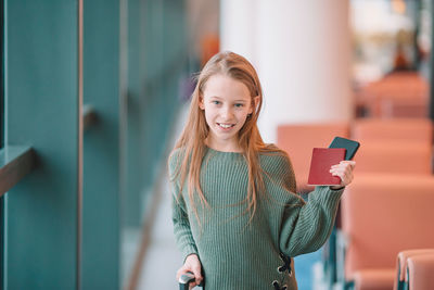 Portrait of smiling young woman holding smart phone