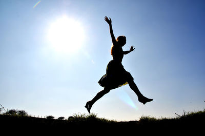 Low angle view of silhouette woman jumping in sky