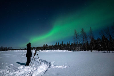 Man walking on snow covered landscape against sky at night