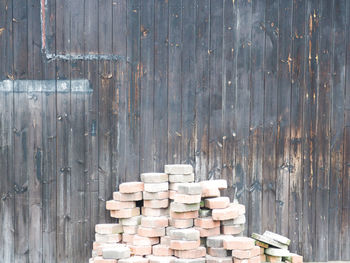 Stack of paving blocks arranged against wooden wall