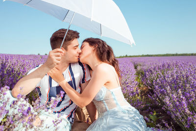 A couple in love under a white umbrella on a lavender field love