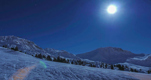 Scenic view of snowcapped mountains against blue sky at night