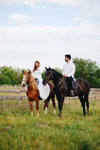 Couple riding horse on field