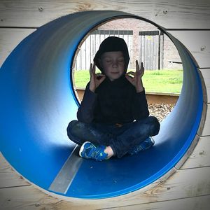 Portrait of boy sitting on slide at playground